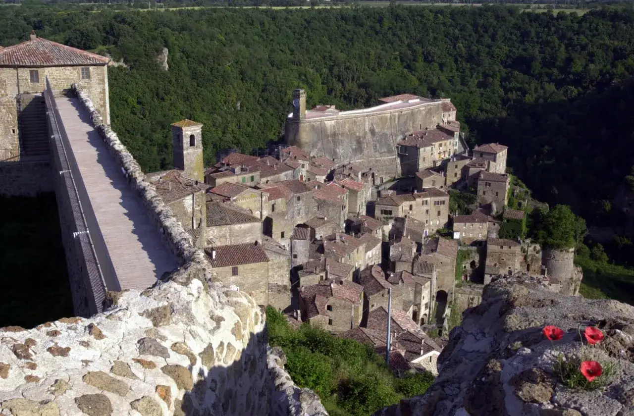 Sorano, Toscana: un borgo medievale arroccato su una rupe tufacea, con case in pietra e tetti rossi che si affacciano su una valle verdeggiante.