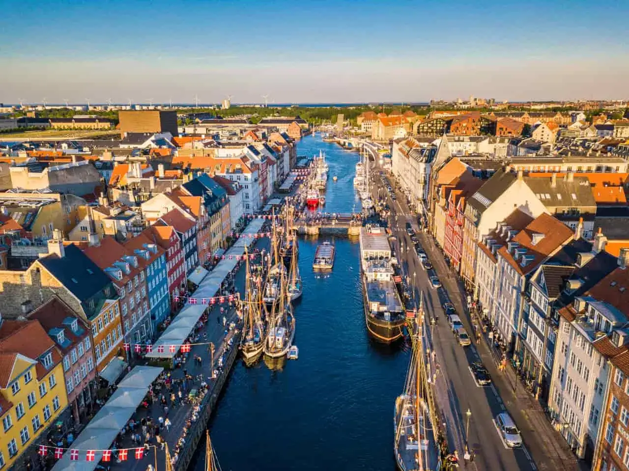 Canali animati nel porto di Copenaghen, con case colorate, barche a vela e un vivace lungomare.