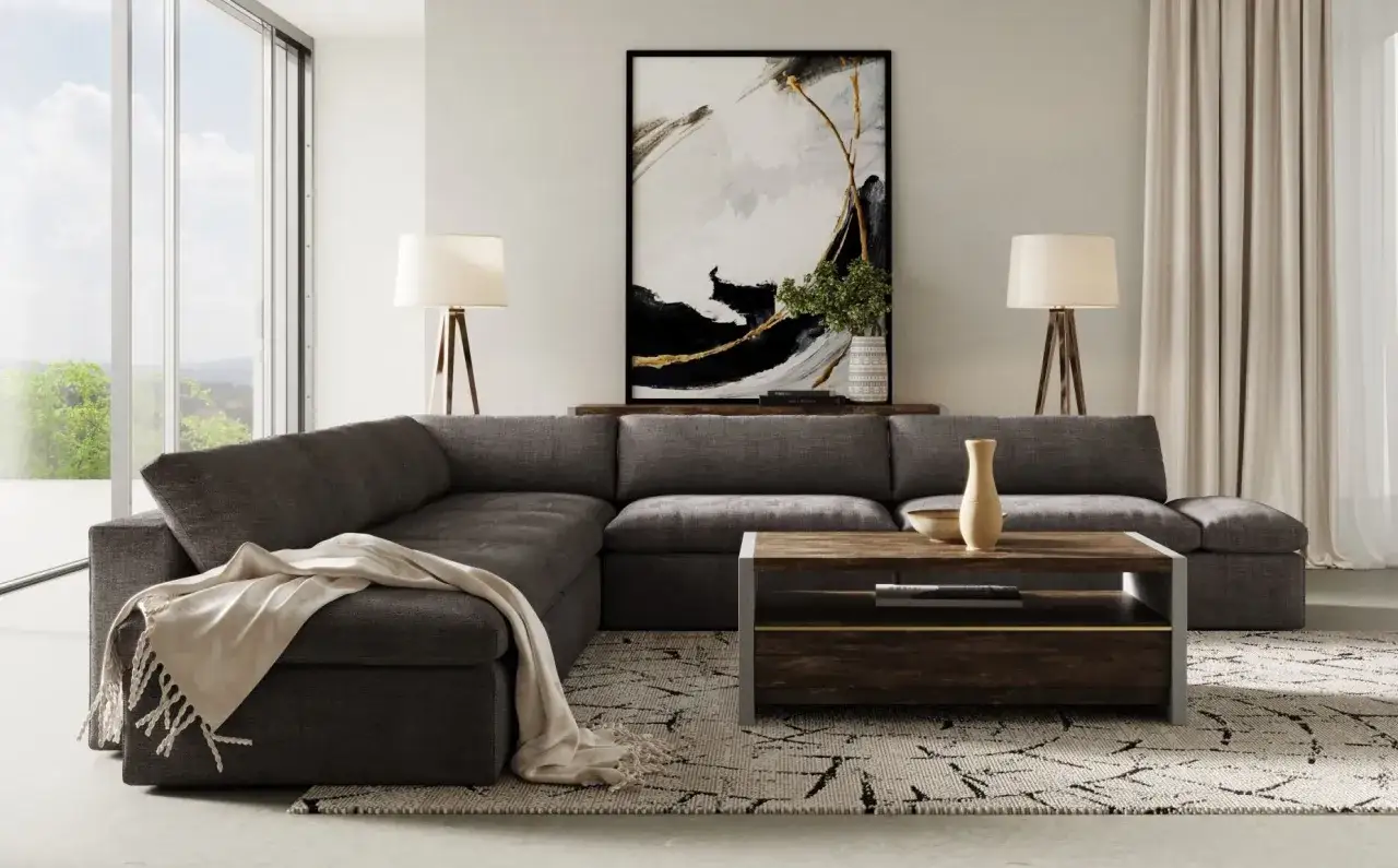Un salon moderne avec un grand canap&eacute; d'angle gris fonc&eacute;, une table basse en bois et m&eacute;tal, et une &oelig;uvre d'art abstraite.