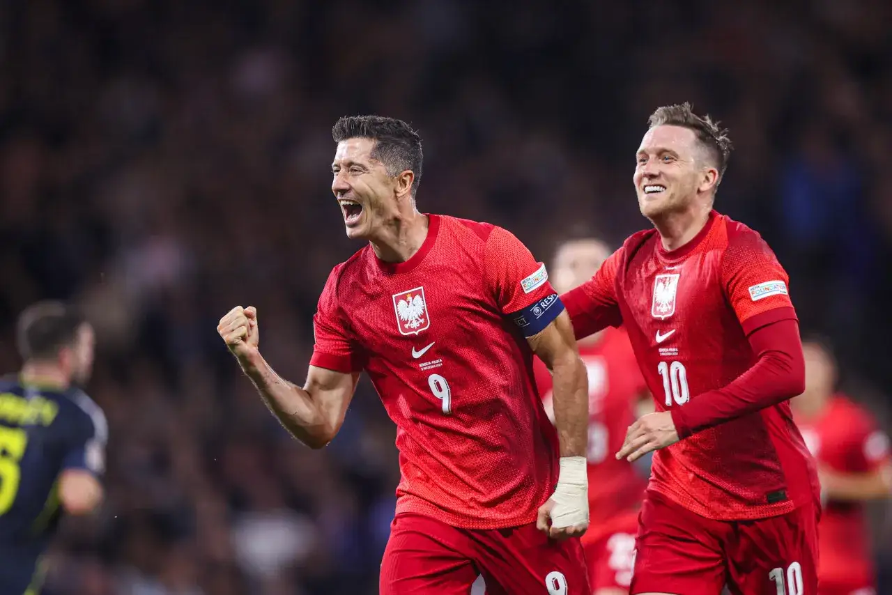 Piłkarze w czerwonych strojach świętują bramkę. Lewandowski z numerem 9 i jego kolega z numerem 10, dumny klub wybitnego reprezentanta.