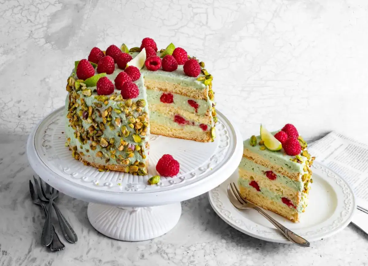 Wyjątkowy tort pistacjowy z malinami i limonką, udekorowany chrupiącymi pistacjami. Idealny na specjalne okazje.