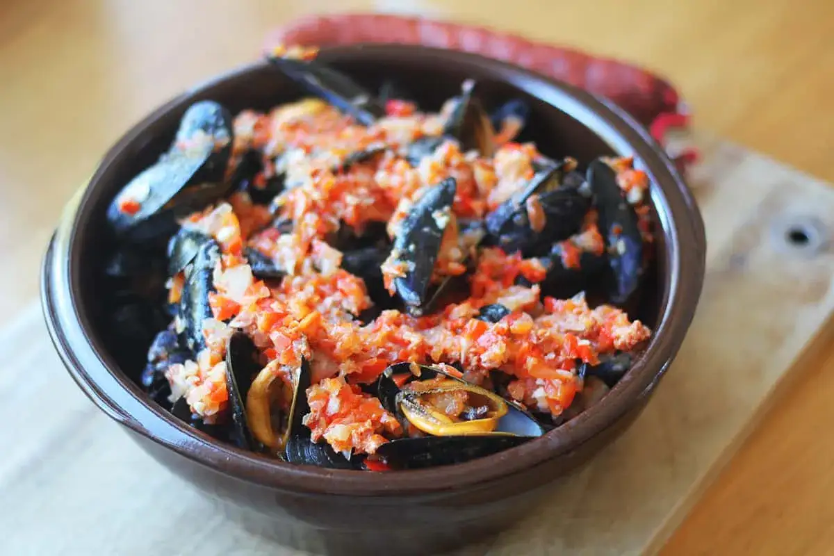 Un bol de moules au chorizo, garnies d'une sauce tomate et poivrons rouges, pr&ecirc;tes &agrave; &ecirc;tre d&eacute;gust&eacute;es.