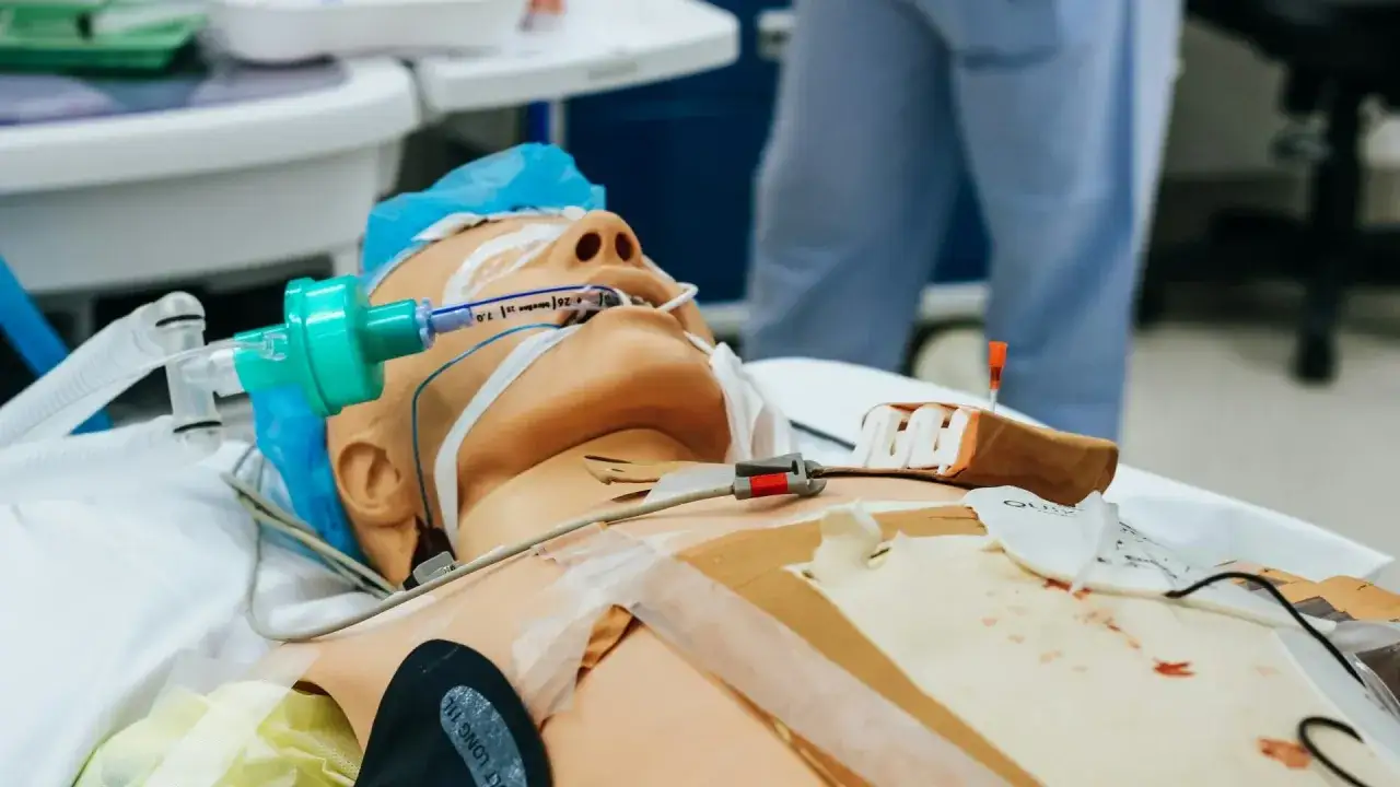 Symulacja medyczna: manekin z rurką intubacyjną i elektrodami, przygotowany do ćwiczeń, kiedy defibrylacja.
