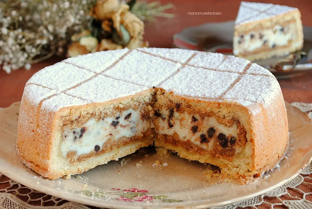 Una fetta di cassata al forno, con ripieno cremoso e gocce di cioccolato, cosparsa di zucchero a velo.