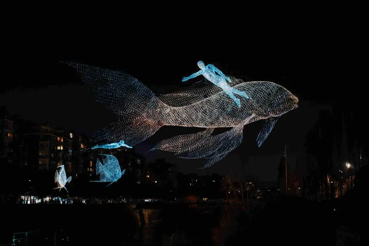 Esculturas luminosas de peces y nadadores flotan en la noche madrileña, como una carrera nocturna de fantasía.