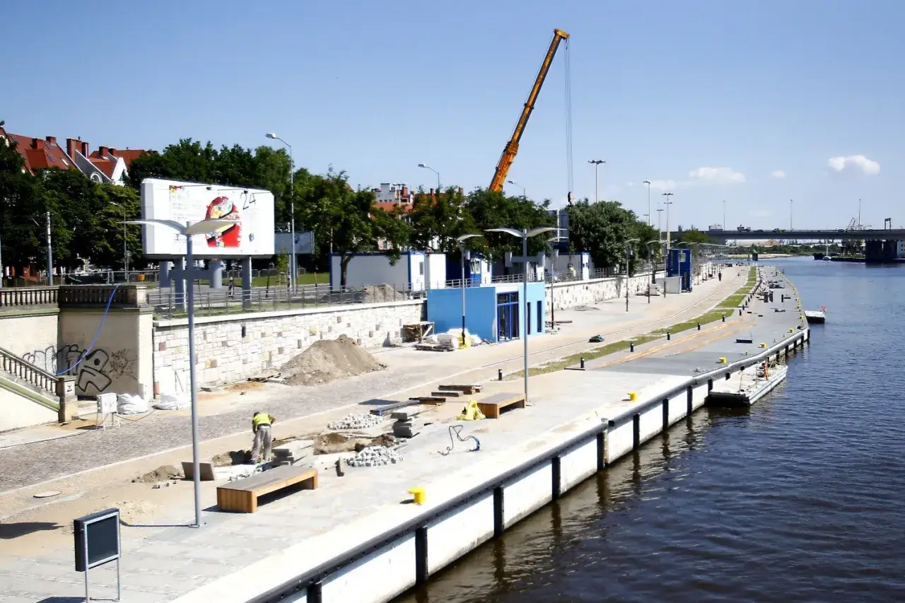Trwa rewitalizacja Bulwaru Piastowskiego w Szczecinie. Widoczny plac budowy, dźwig i pracownik.
