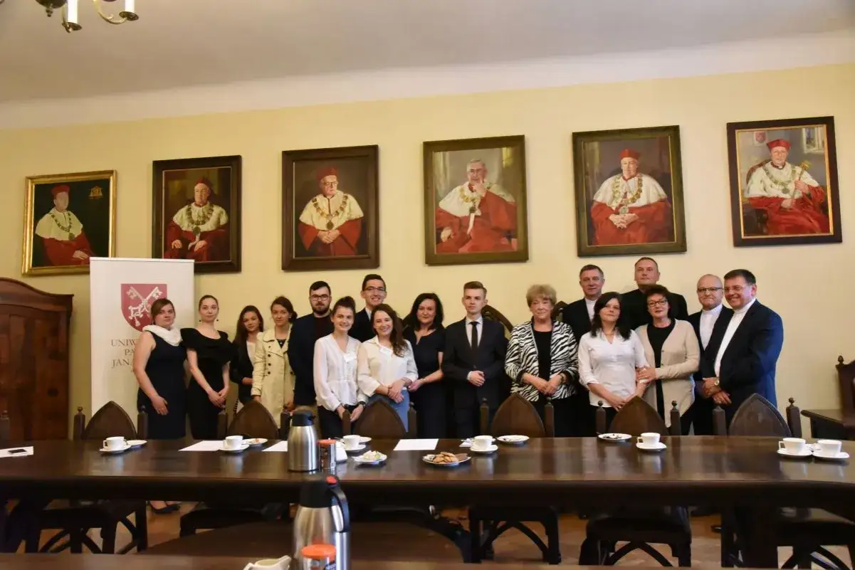 Grupa osób pozuje przed portretami profesorów. Na pierwszym planie widać stół z filiżankami. To studenci Uniwersytetu Papieskiego, którzy wybrali ciekawe kierunki studiów.