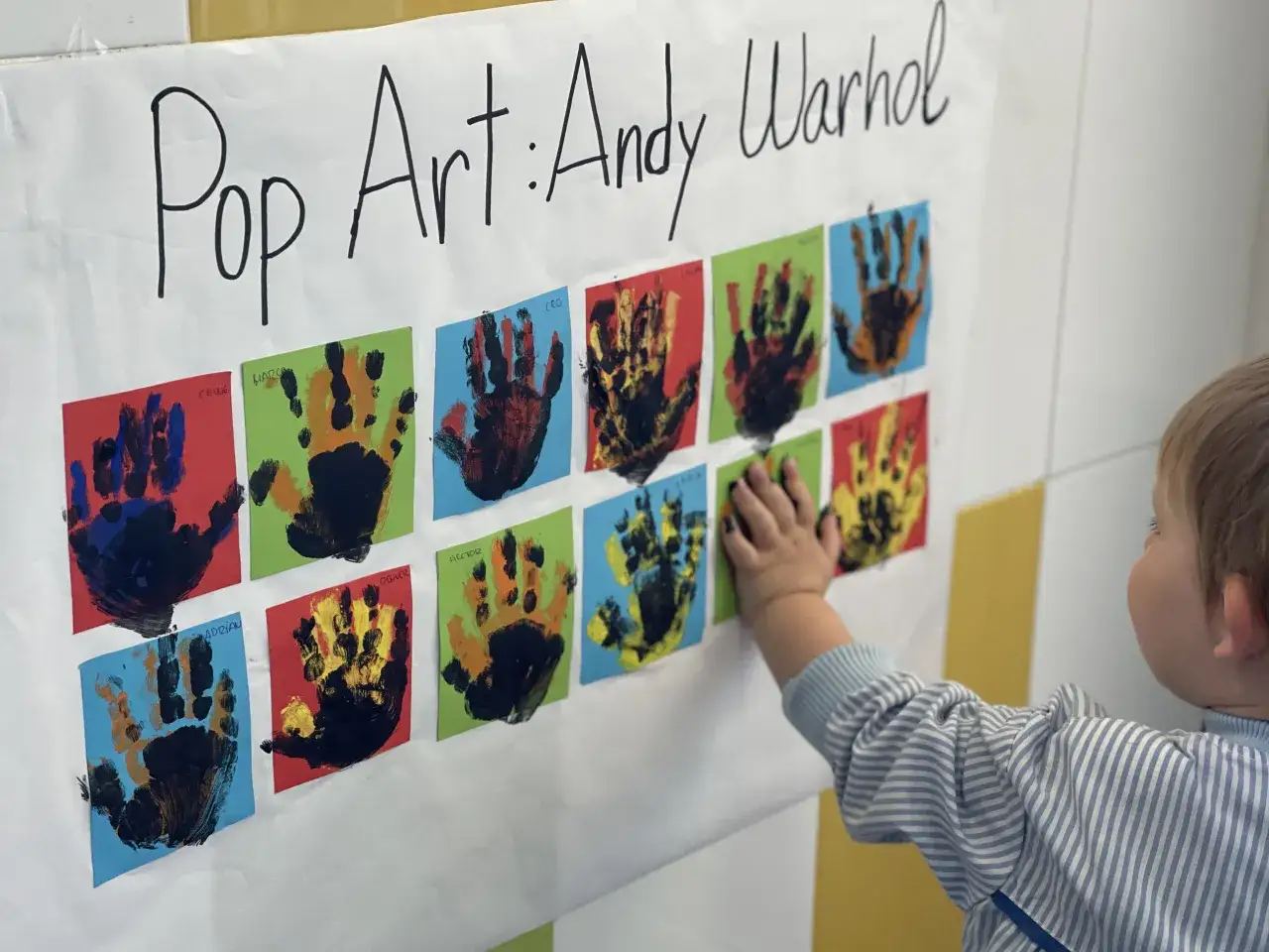 Manos pequeñas crean arte pop inspirado en Andy Warhol. Un niño toca una obra colorida, parte de un proyecto artístico infantil.