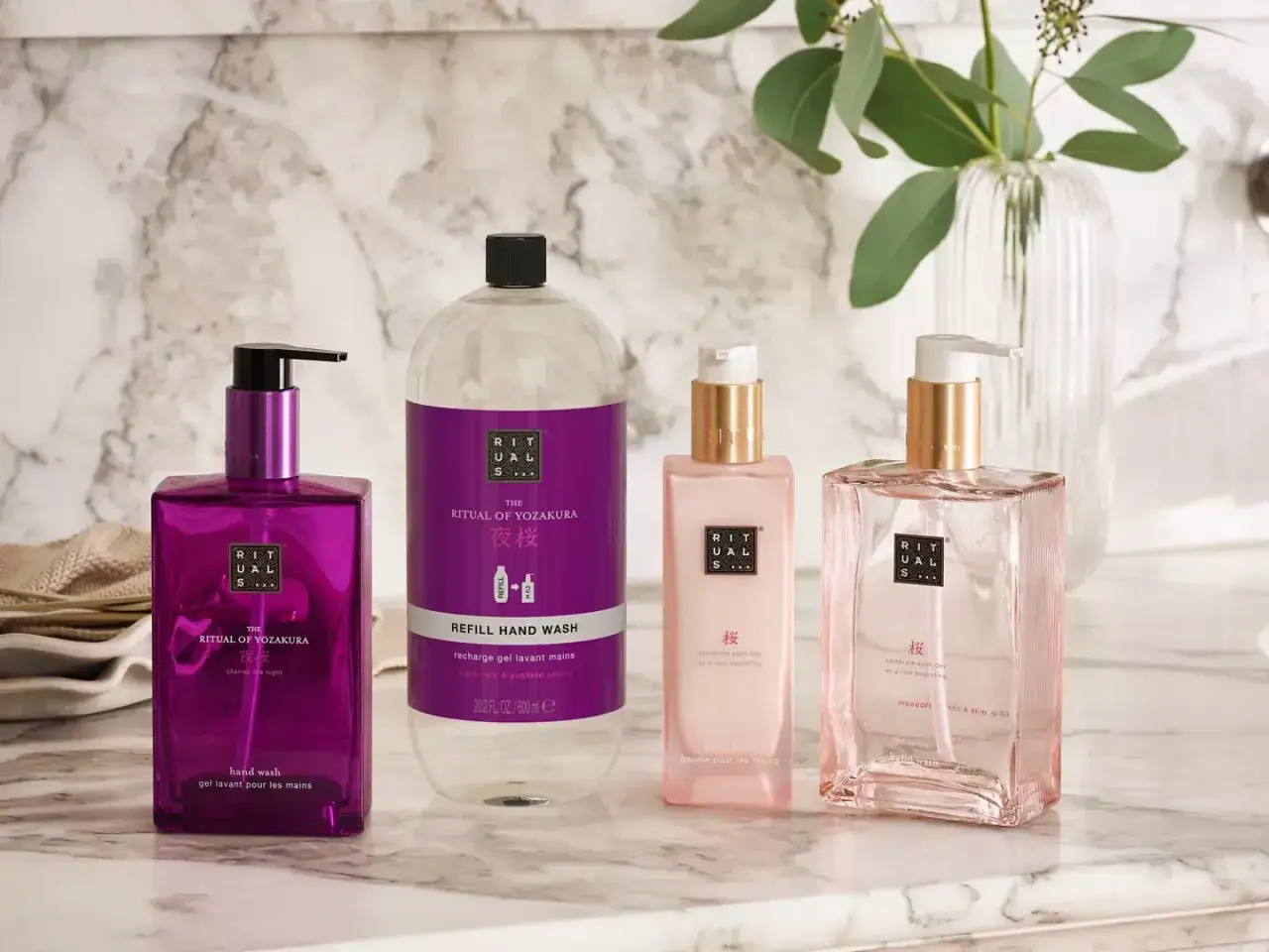 Rituals to marka luksusowych kosmetyków. Na zdjęciu cztery produkty: fioletowy żel do rąk, duży refill żelu do rąk, różowy balsam do rąk i różowy żel do rąk.