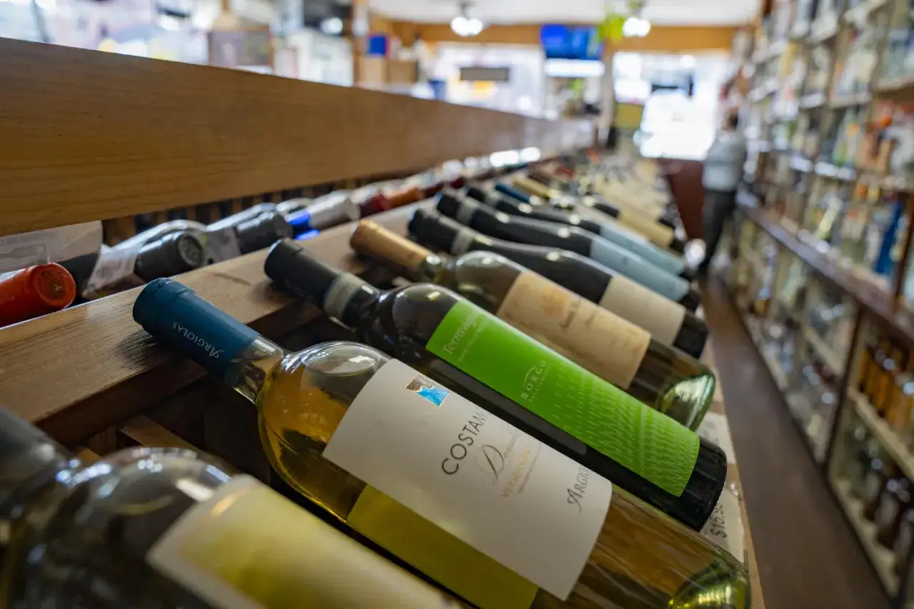 Estanter&iacute;as llenas de botellas de vino, algunas con etiquetas verdes y blancas, sugieren una selecci&oacute;n de vinos mas vendidos en Espa&ntilde;a.