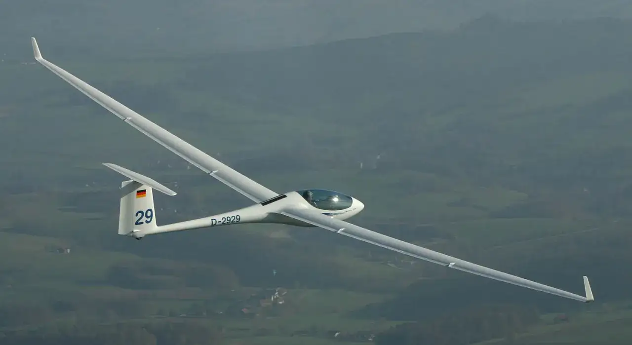 Ein Segelflugzeug ASG 29 mit der Kennung D-2929 fliegt &uuml;ber eine gr&uuml;ne Landschaft.