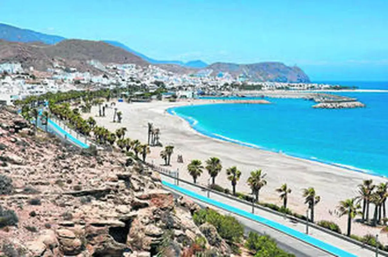 Descubre qué ver en Carboneras: playa, palmeras y el mar azul turquesa. Un paraíso costero con montañas al fondo.