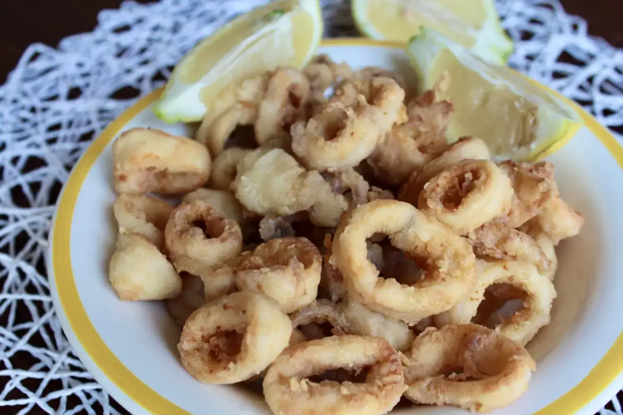 Calamari croccanti in friggitrice ad aria, serviti con spicchi di limone fresco. Un antipasto leggero e gustoso, perfetto per ogni occasione.