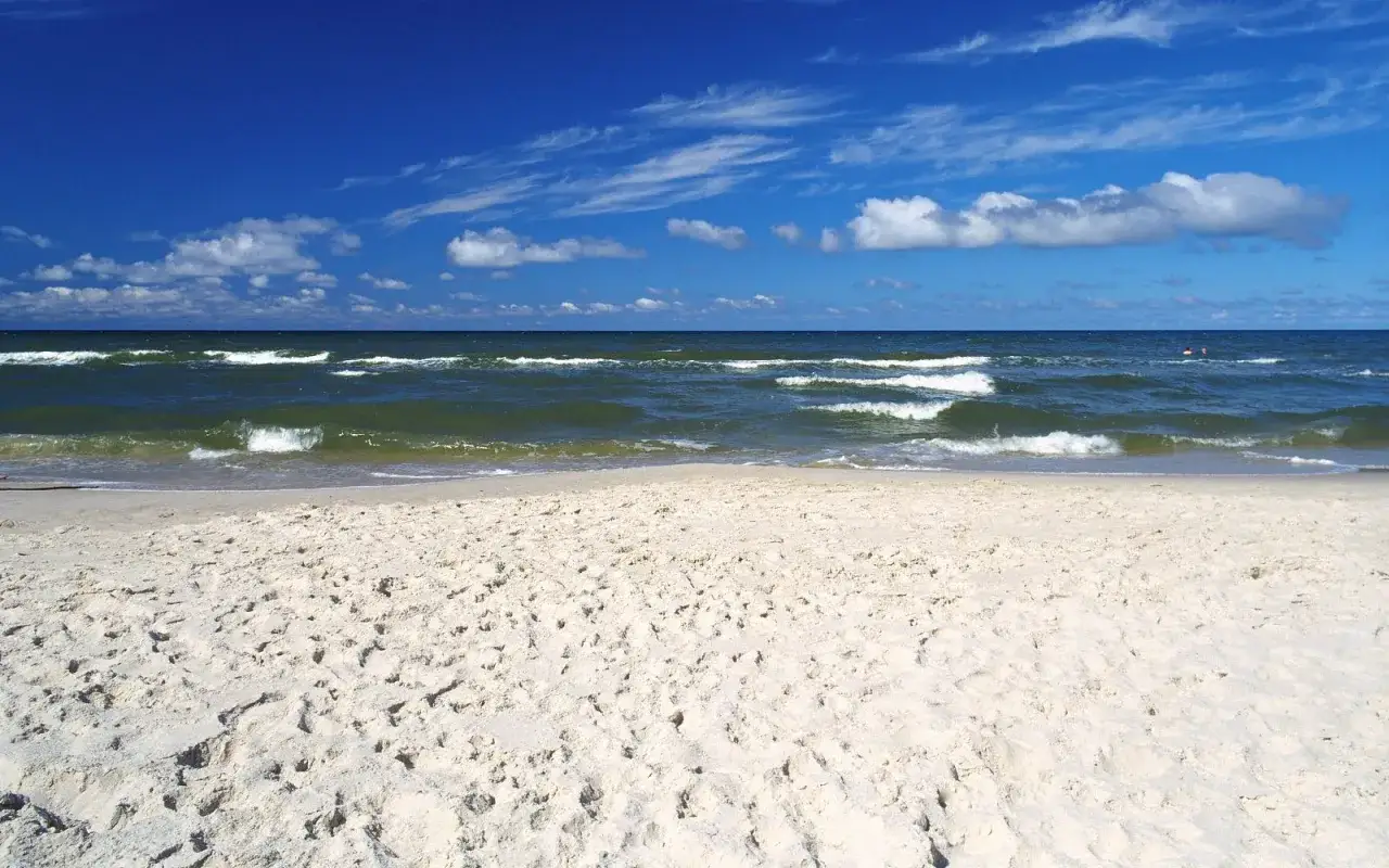 Piękna plaża w Choczewie, z piaszczystym brzegiem i falującym morzem pod błękitnym niebem.