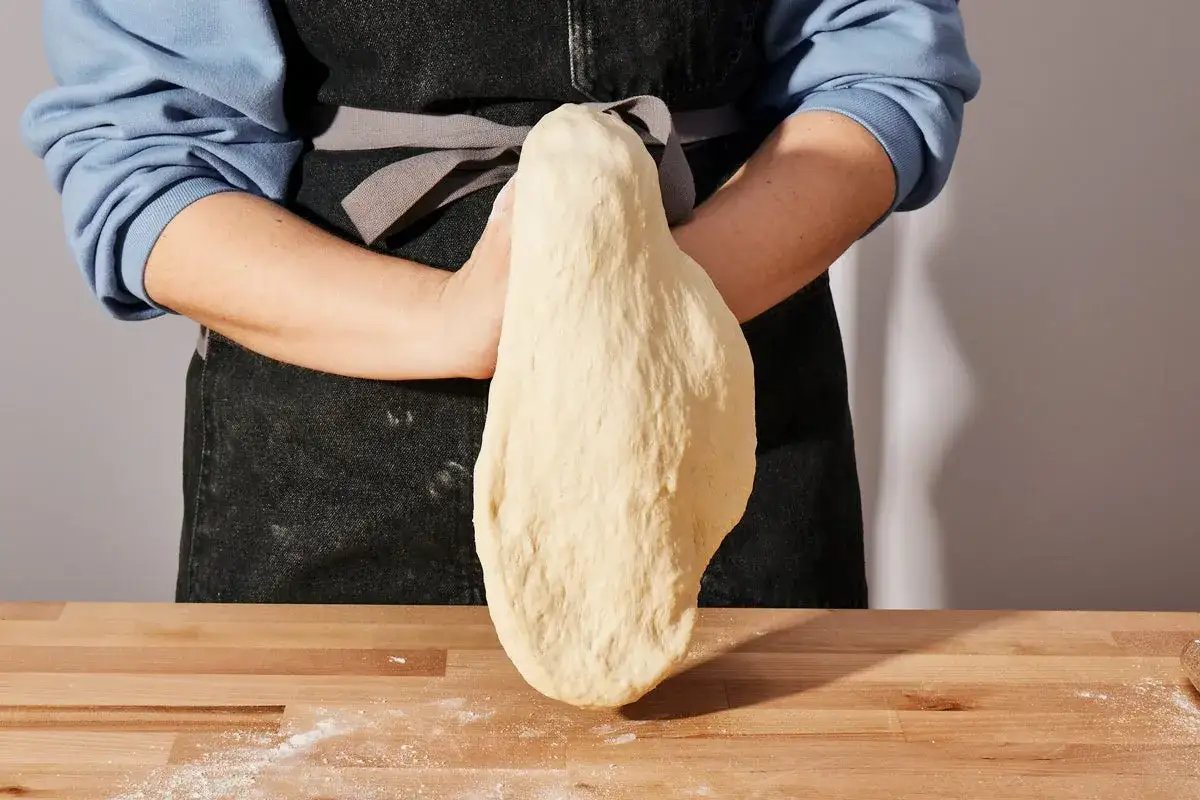 Ręce formują ciasto na pizzę, które będzie cienkie i chrupiące. Idealna baza na domową pizzę.