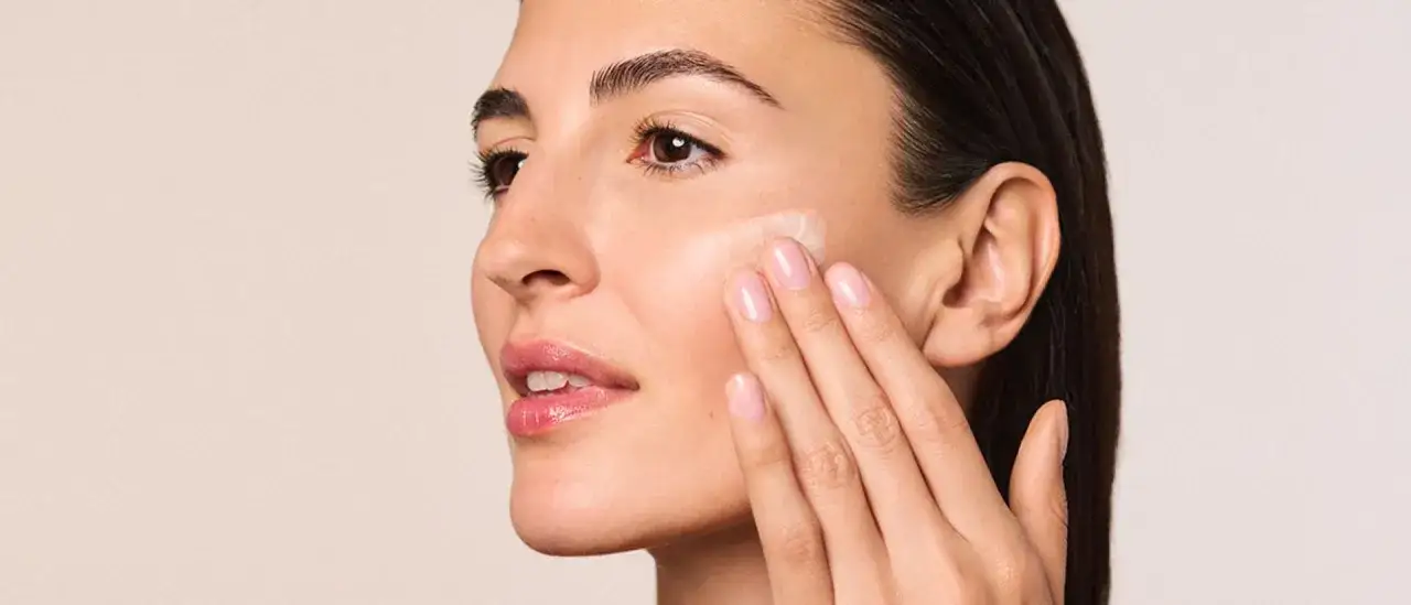 Eine Frau trägt eine Creme auf ihr Gesicht auf, die für die Tages- und Nachtpflege geeignet ist.