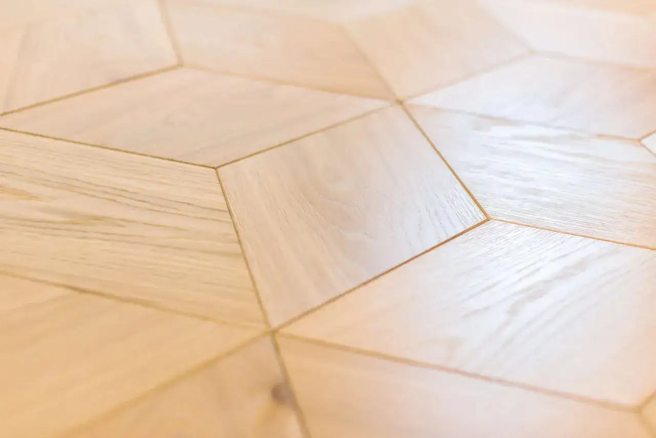 Calepinage parquet en bois clair, motif g&eacute;om&eacute;trique en losanges. L'effet visuel est moderne et lumineux.
