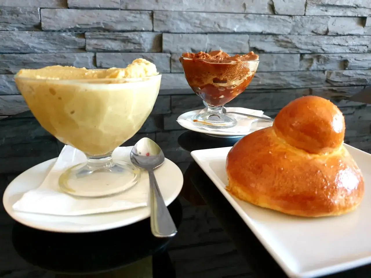 Une brioche italienne dor&eacute;e, accompagn&eacute;e de deux coupes de glace, l'une &agrave; la vanille, l'autre au chocolat.