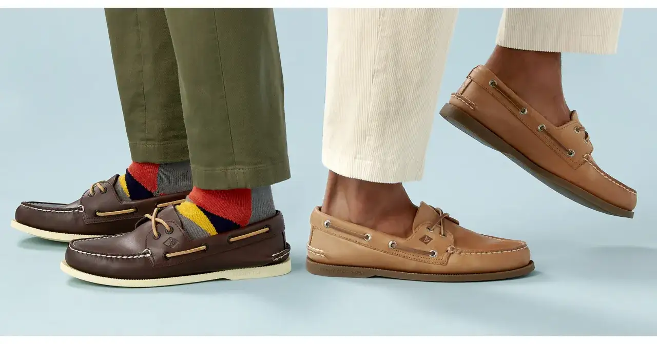 Deux paires de chaussures bateau, l'une marron avec des chaussettes colorées, l'autre beige, sur fond bleu clair.