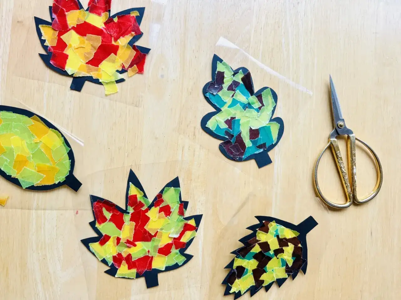 Bunte Blätter aus Seidenpapier, perfekt für ein Herbstgedicht in der Grundschule. Schere liegt bereit.