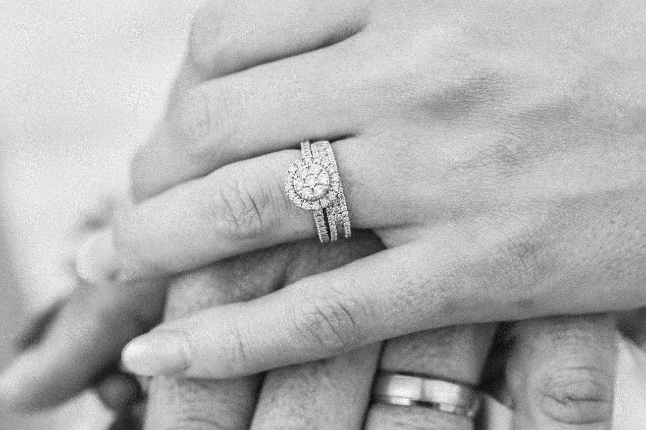 Mani intrecciate, dove si mette l'anello di fidanzamento donna: un trio di fedi scintillanti su un dito, simbolo di un amore eterno.