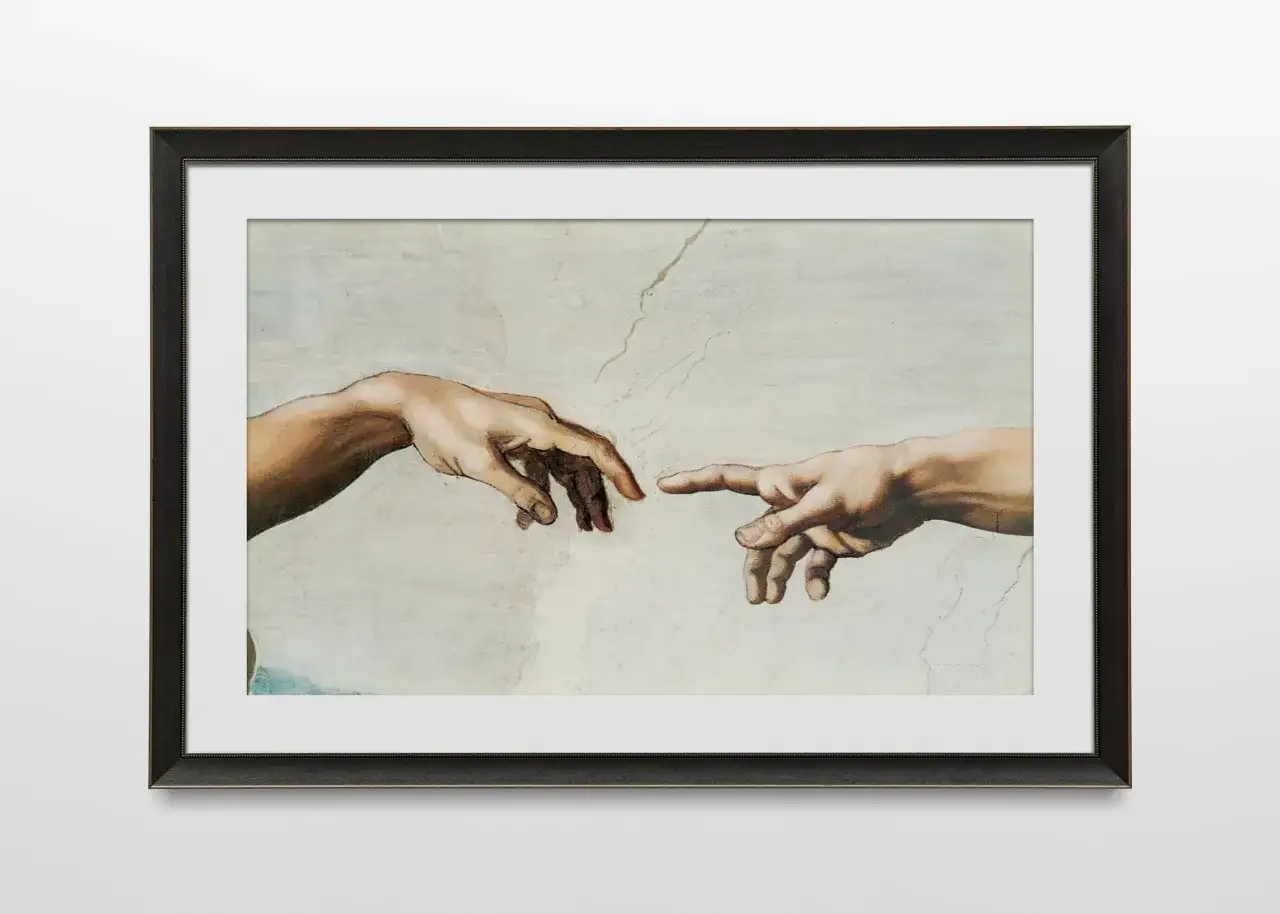 Le tableau encadré montre la célèbre fresque de Michel-Ange, La Création d'Adam. Les mains de Dieu et d'Adam se tendent l'une vers l'autre, symbolisant la transmission de la vie. La signification des mains de Michel-Ange est profonde.