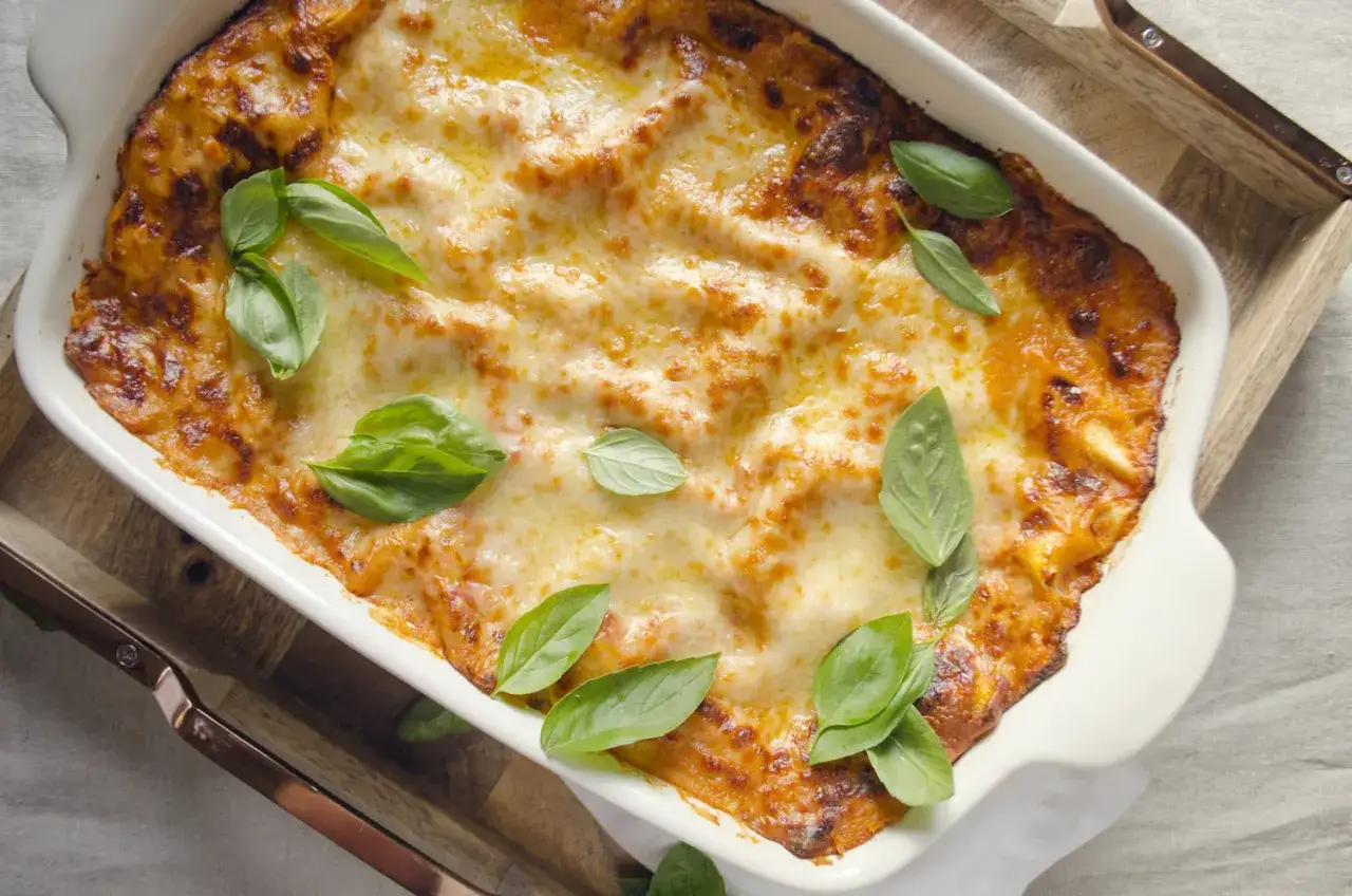 En gyllene, bubblande italiensk lasagne toppad med färsk basilika, redo att serveras.