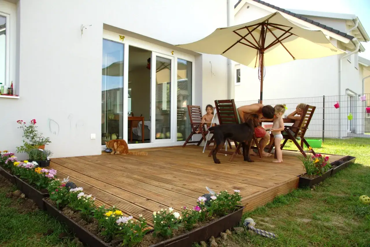 Gemütliche Sitzecke im Garten auf dem Holzdeck. Kinder, ein Hund und eine Katze genießen den sonnigen Tag.