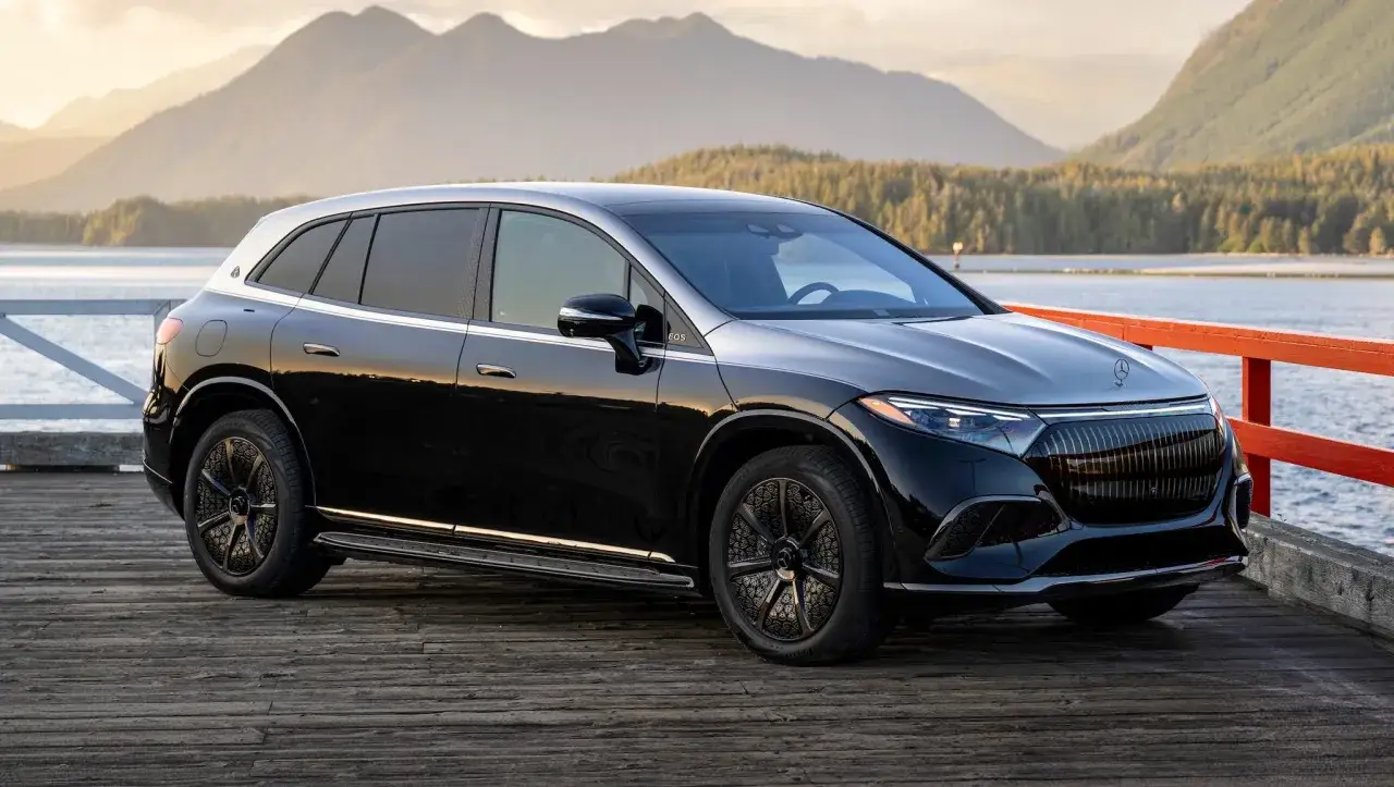 Elegancki czarny Maybach SUV na drewnianym molo, z górami i jeziorem w tle.