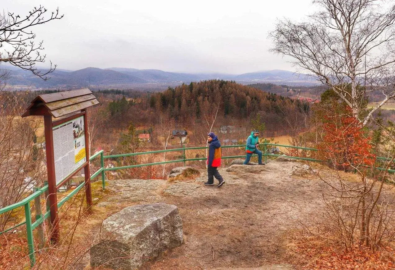 Widok z góry Witosza na jesienny krajobraz. Dwie osoby podziwiają panoramę, obok tablica informacyjna.
