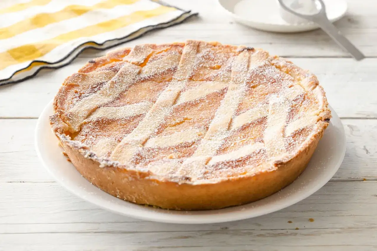Pastiera napoletana ricetta originale, una torta dorata con decorazione a griglia e zucchero a velo, pronta per essere gustata.