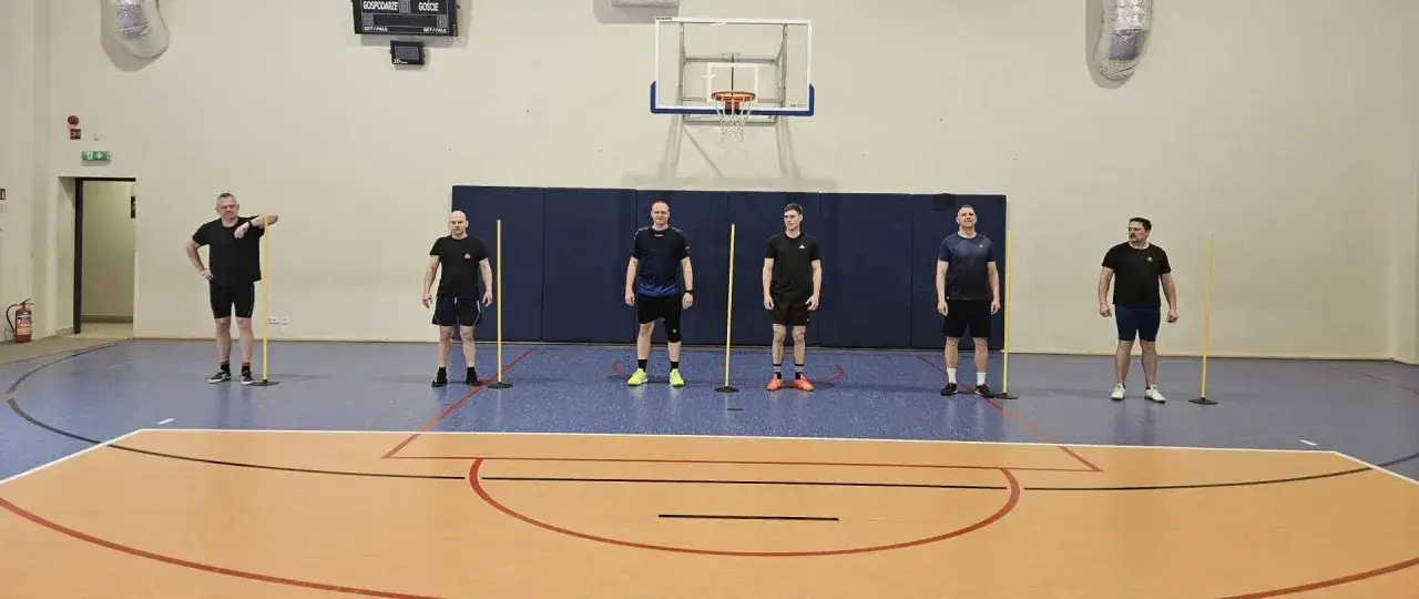 Strażacy w hali sportowej przygotowują się do testów sprawnościowych. Ich praca w straży pożarnej wymaga doskonałej kondycji.