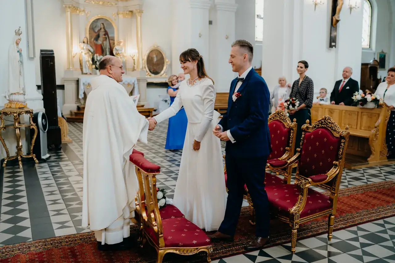 Para młoda w kościele, podczas uroczystości ślub i chrzest w jednym. Ksiądz błogosławi parę.