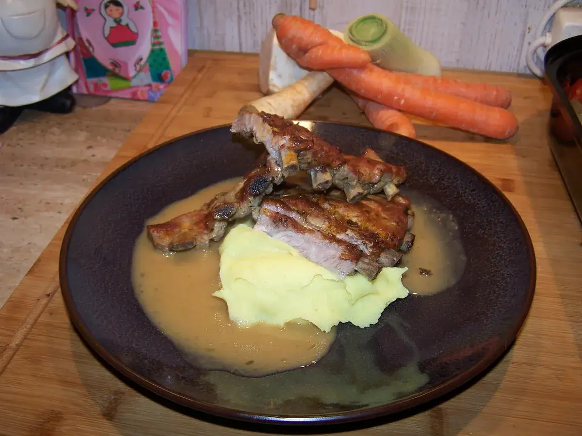 Saftige Rippchen in der Pfanne geschmort, serviert mit Kartoffelp&uuml;ree und einer k&ouml;stlichen Sauce. Daneben liegen frisches Gem&uuml;se wie Karotten und Lauch.