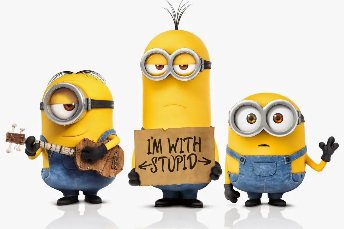 Trzech minionków. Jeden gra na ukulele, drugi trzyma tabliczkę 