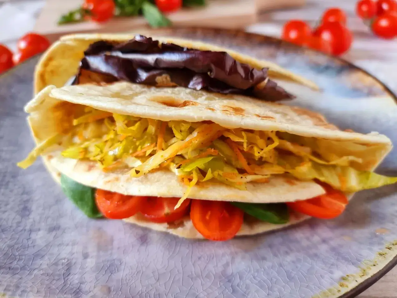Piadina farcita con insalata, pomodorini e verdure croccanti. Un'idea gustosa su come farcirla per un pasto veloce e saporito.
