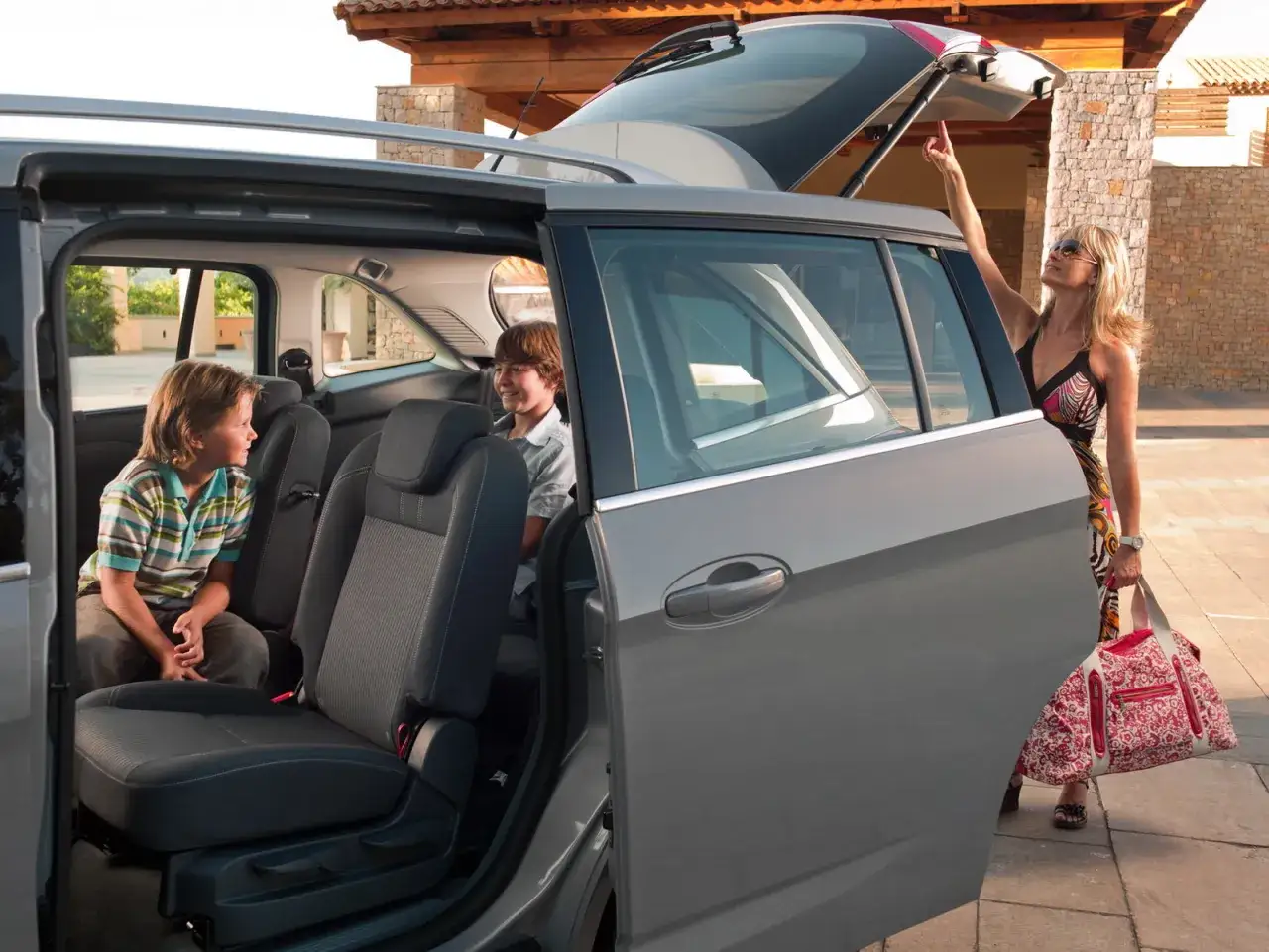 Bambini seduti sui sedili posteriori di una Ford C-Max 7 posti, con la madre che chiude il bagagliaio.