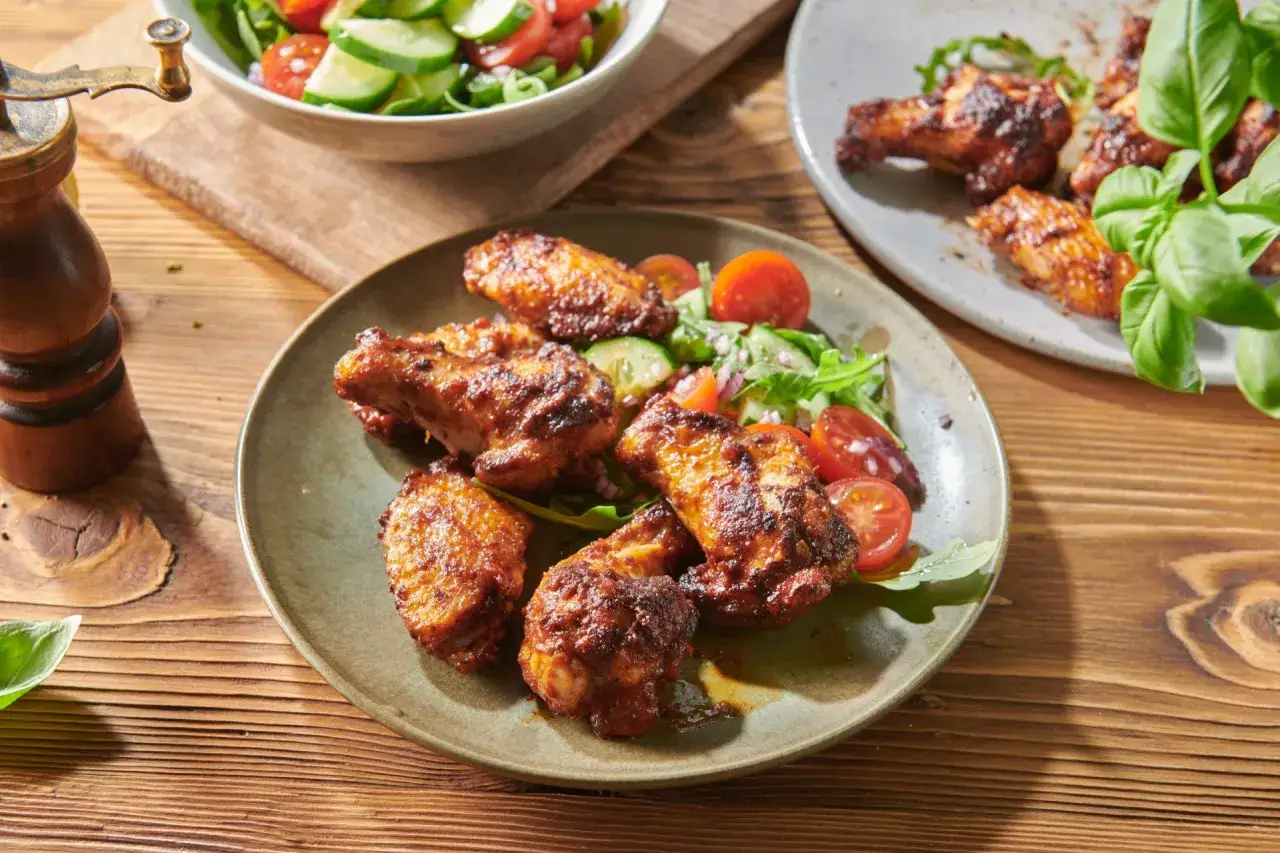 Pyszne, przypieczone skrzydełka kurczaka z sałatką. Idealne, gdy zastanawiasz się, w jakiej temperaturze piec skrzydełka, by były chrupiące.