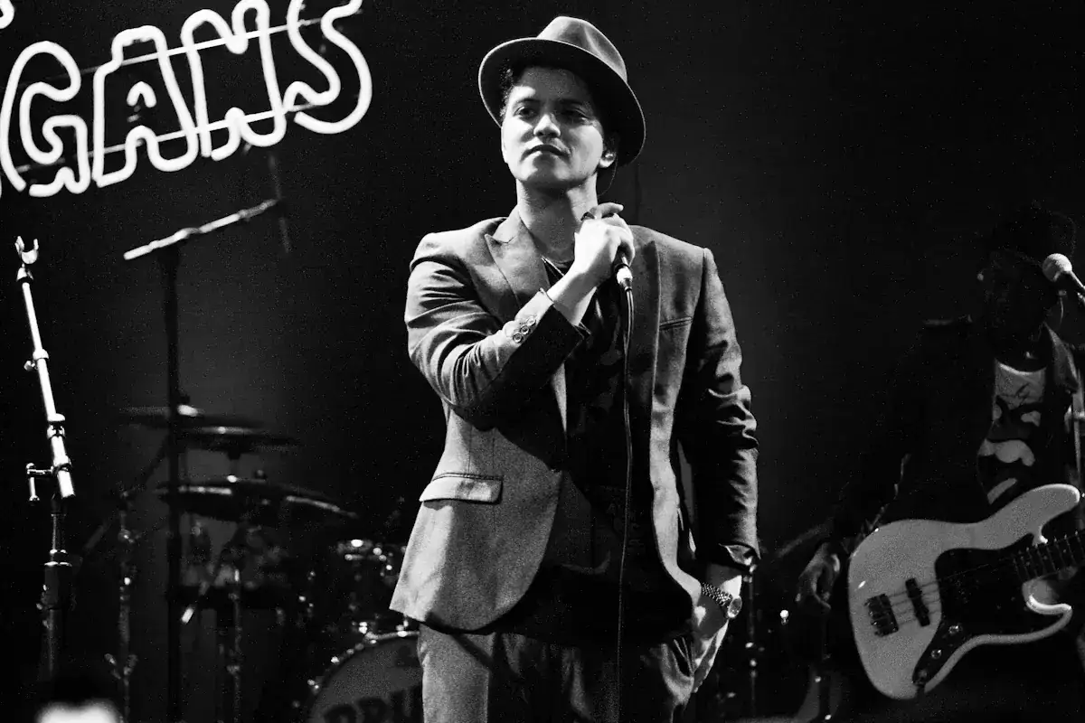Bruno Mars i Sverige, med hatt och kavaj, sjunger i mikrofonen på scenen.