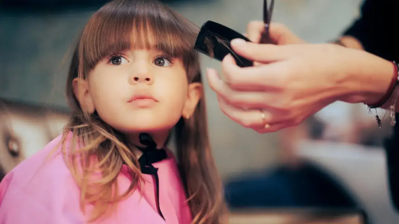 Ein kleines Mädchen mit Pony bekommt einen neuen Haarschnitt.