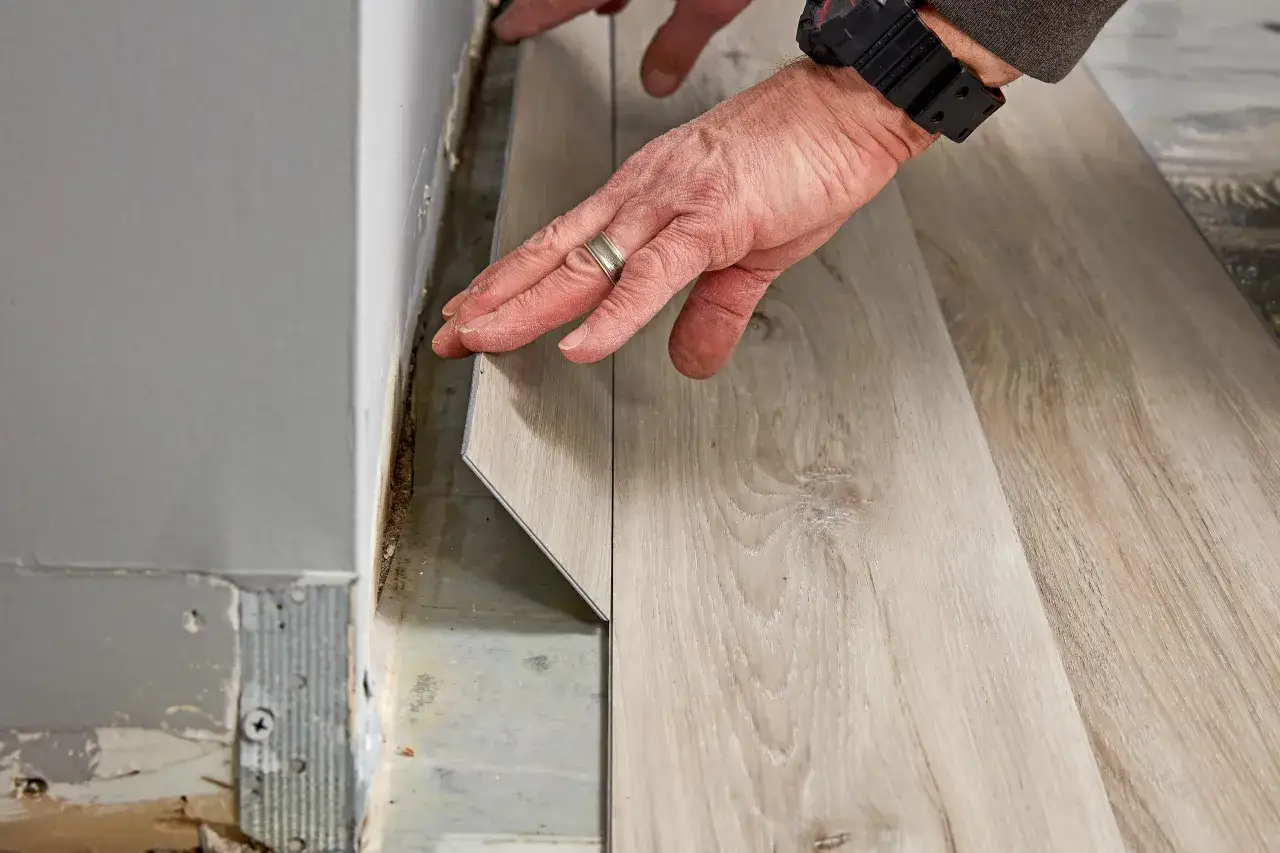 Hands carefully lay down a plank during waterproof flooring installation, creating a beautiful, durable surface.