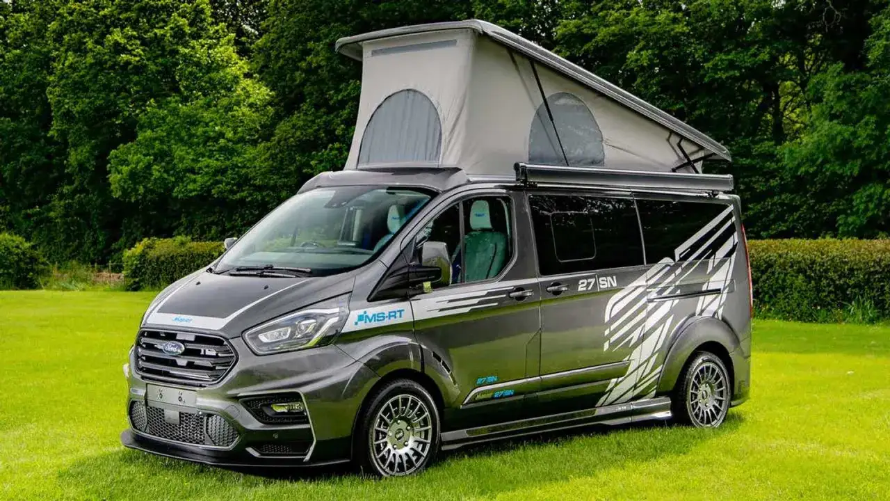 Un'avventurosa auto camperizzata grigia con tetto a soffietto, pronta per esplorare la natura.