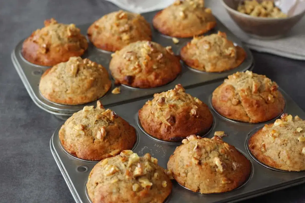 Frisch gebackene Bananen Nuss Muffins in einer Muffinform, garniert mit Walnussstücken.