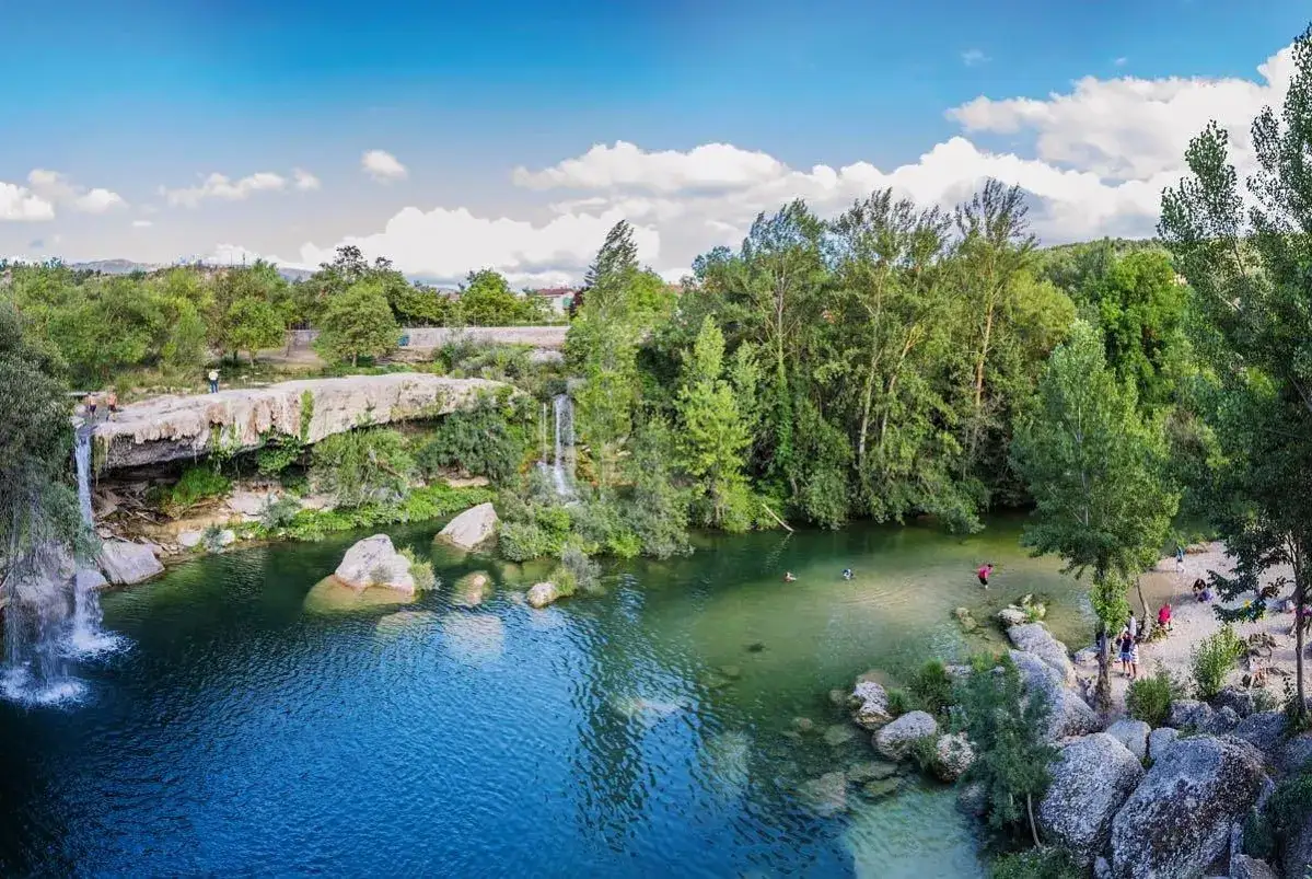 La cascada del peñón, con aguas cristalinas y rodeada de vegetación exuberante, invita a refrescarse. Personas disfrutan del baño y la naturaleza.