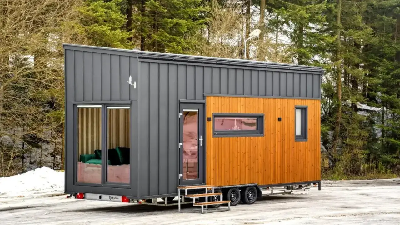 Casa m&oacute;vil moderna con revestimiento de madera y metal, un ejemplo de conciencia ecol&oacute;gica y vida minimalista en un entorno boscoso.