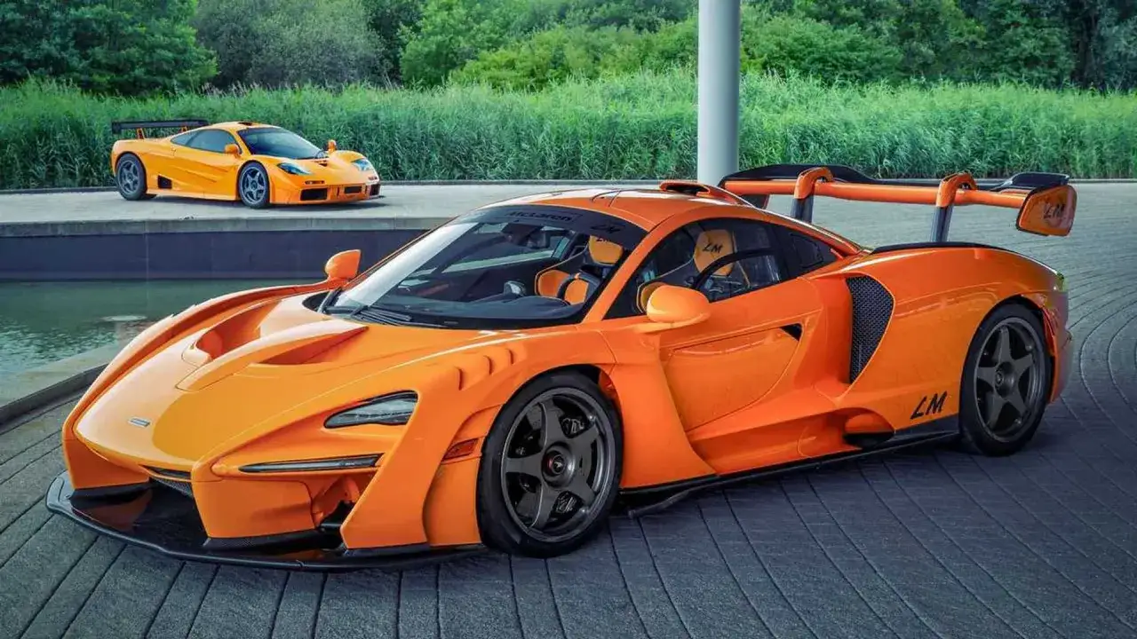 Zwei orangefarbene McLaren, ein moderner McLaren Senna LM und ein klassischer McLaren F1, stehen nebeneinander.