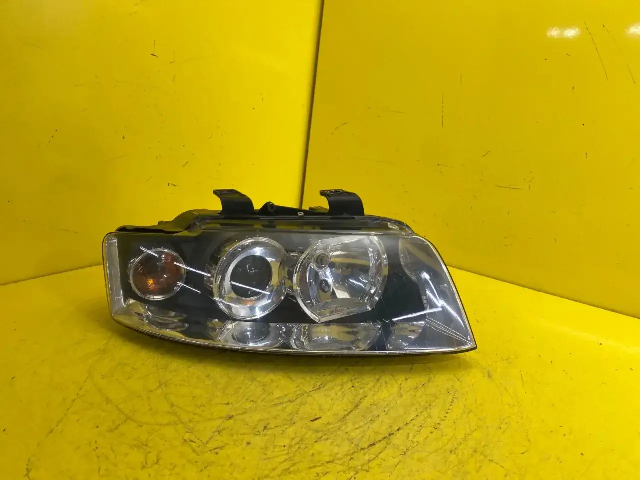 Reflektor przedni do Audi A4 B6, z pomarańczową żar&oacute;wką kierunkowskazu i okrągłymi soczewkami.