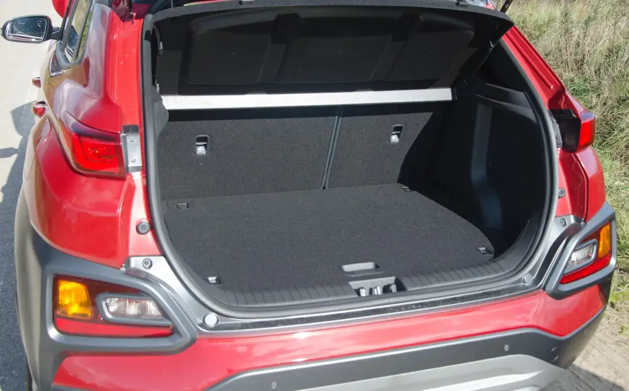 Czerwony Hyundai Kona Hybrid z otwartym bagażnikiem. Wnętrze jest czyste i przestronne, gotowe na bagaże.