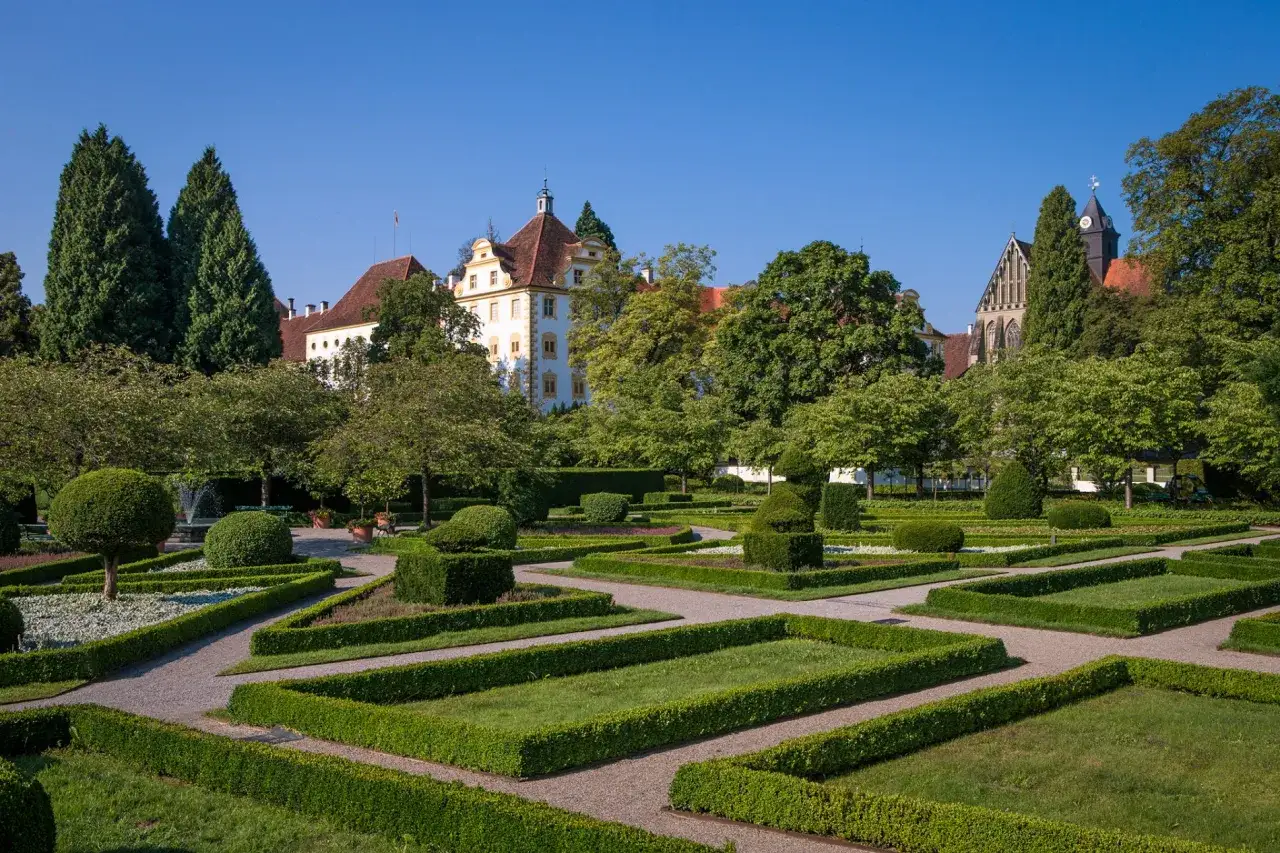 Barocker Garten mit geometrischen Beeten und einem Schloss im Hintergrund. Das Kloster Salem erstrahlt in voller Pracht.