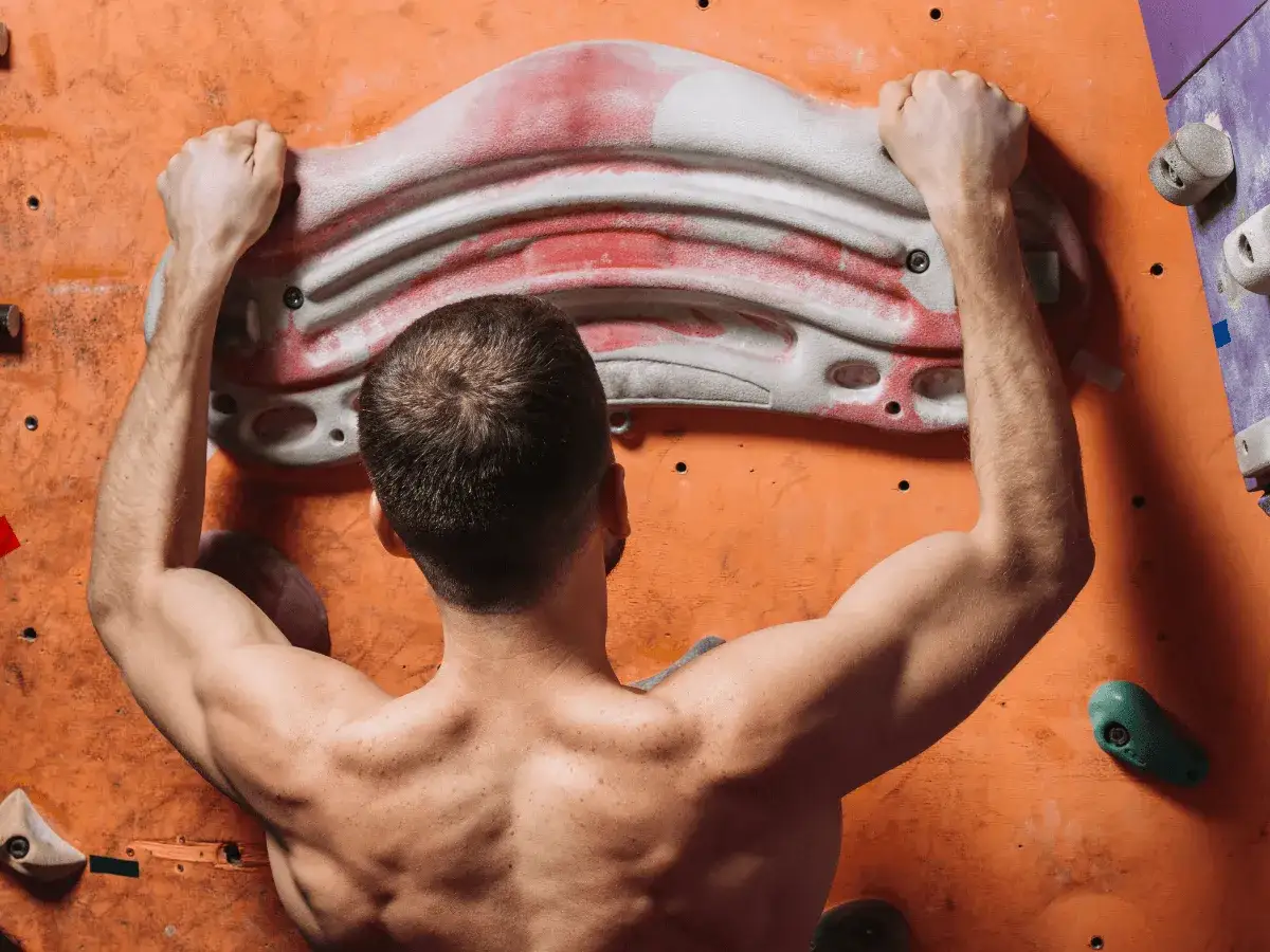 Mann trainiert Fingerkraft am Hangboard. Starke Arme und R&uuml;cken sind sichtbar.